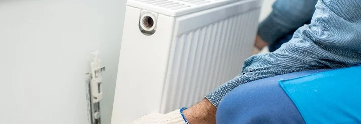 Person montiert Heizkörper an Wand